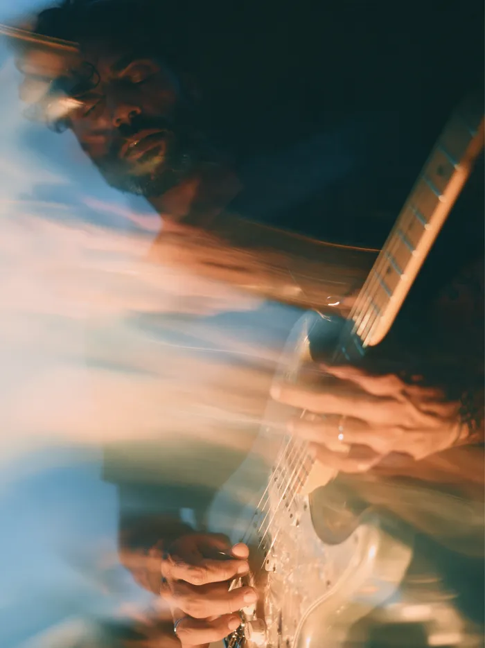A guitarist bent over the neck in warm stage light