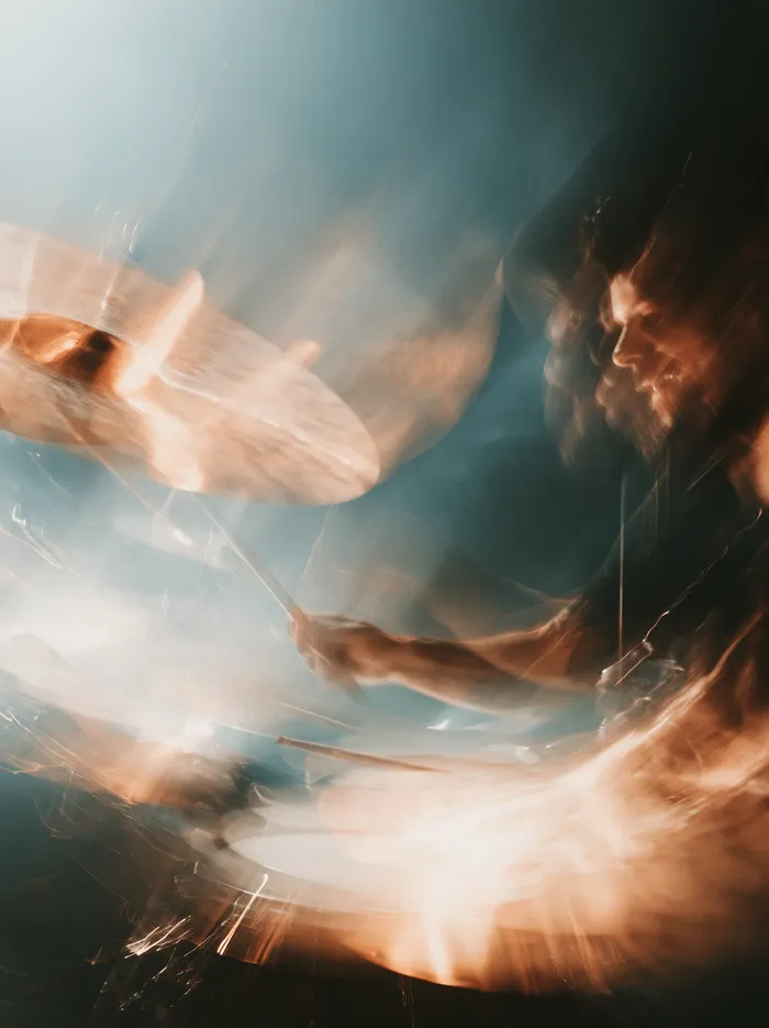 A drummer in motion blur, sticks over the cymbals