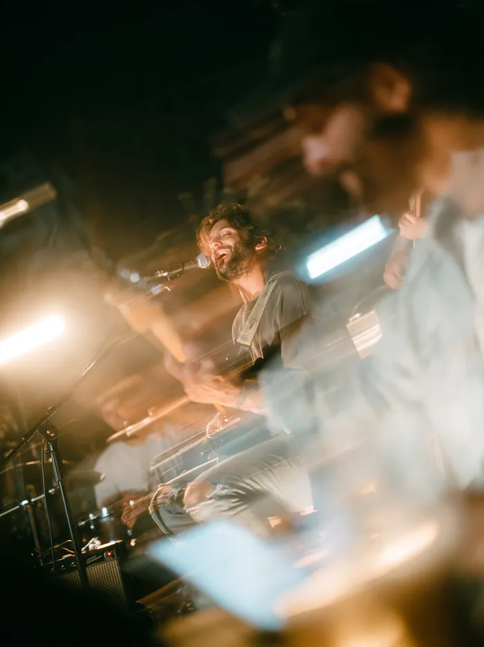 A band on a small stage, singer and guitarist in warm light